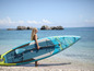 Žena drží nafukovací paddleboard Aqua Marina Hyper na pláži.