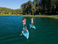 Dva lidé pádlují na paddleboardech na jezeře.