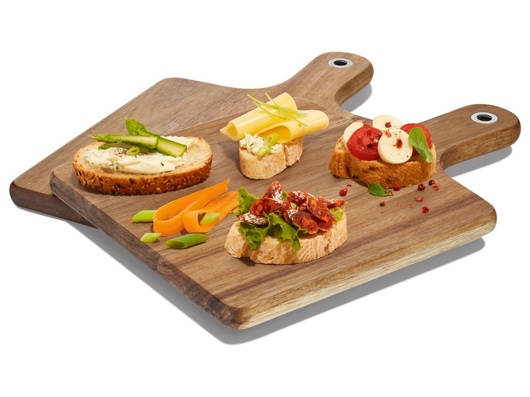 Výběr malých chlebů se sýrem, salámem, rajčaty a mozzarellou na dřevěném prkénku.