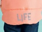 Růžová péřová bunda s nápisem 'LIFE' na zádech.
