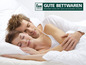 Pár spí v posteli s polštáři a peřinami od Frankenstolz Schlafkomfort.