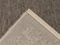Detail hnědého tkaného koberce s béžovým okrajem.