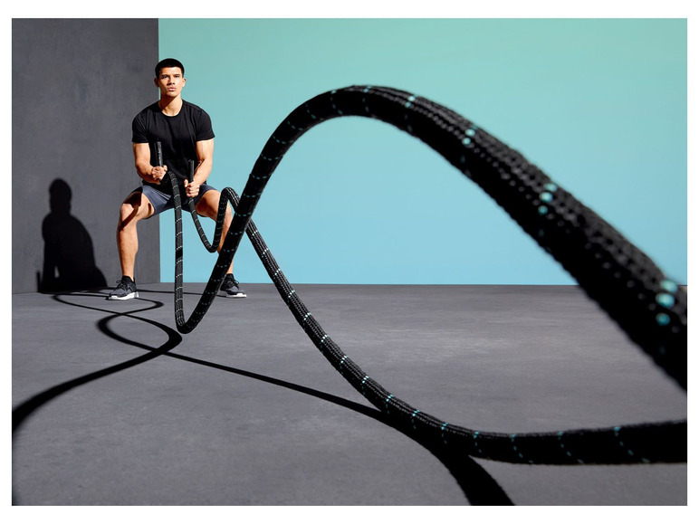Muž cvičí s těžkým lanem na fitness.