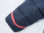 Rukáv tmavě modré zimní bundy s červeným lemem.