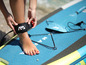 Žena si připevňuje leash na nohu na paddleboardu Aqua Marina.