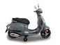 Šedý elektrický skútr Vespa pro děti s pomocnými kolečky.