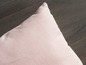 Růžový polštář na dřevěné podlaze.