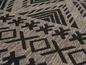 Detail koberce s geometrickým vzorem v černé a šedé barvě.