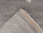 Detail šedého koberce s béžovým okrajem.