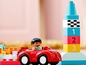Červené auto s LEGO Duplo figurkou vedle věže s kostkami s čísly.