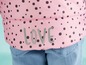 Růžová bunda s bílými puntíky a nápisem 'LOVE'.