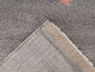 Detail šedého koberce s růžovými akcenty.