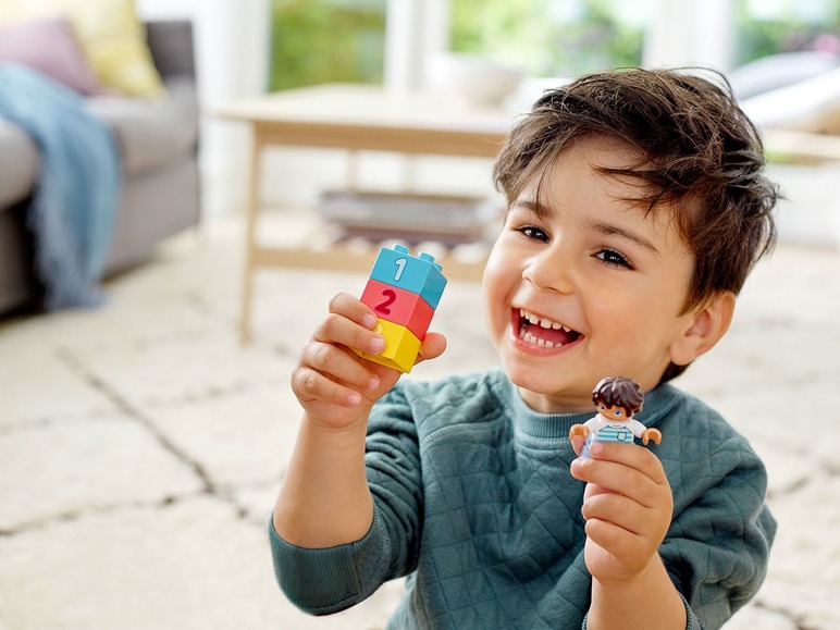 Chlapec si hraje s LEGO DUPLO kostkami a figurkou.