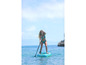 Žena pádluje na nafukovacím paddleboardu v tyrkysové vodě.