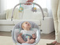 Dítě sedí v houpací židli Fisher-Price s hrazdou s lvem a slonem.