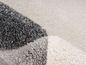 Detail koberce v šedé, bílé a světle šedé barvě.