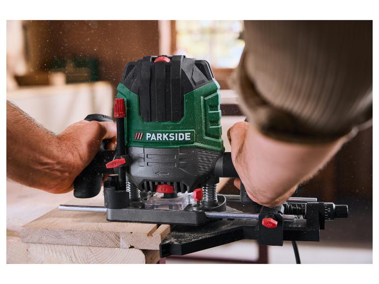 Muž používá frézku k opracování kusu dřeva, s pilinami ve vzduchu.