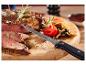 Grilovaný steak s nakrájenou cibulí a rajčaty na dřevěném prkénku s nožem.