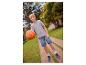 Chlapec v šedém tričku, džínových šortkách a teniskách drží basketbalový míč na cestě.