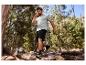 Muž v šedém tričku a černých šortkách běhá v lese.