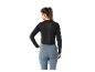 Žena má na sobě černý sportovní top a modré legíny.