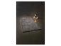 Šedý huňatý koberec a stolní lampa na knihách na tmavém pozadí.