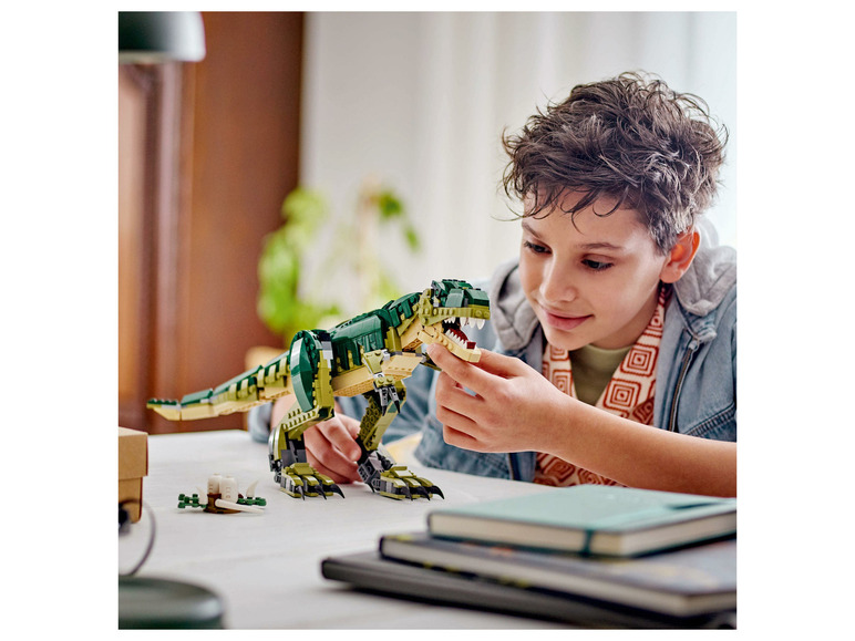 Dítě si hraje s LEGO dinosaurem T-Rex.