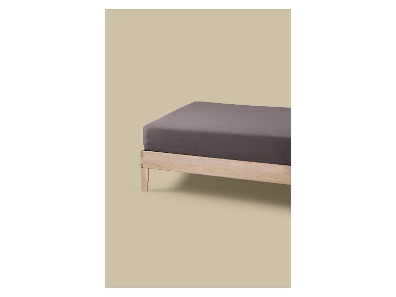 Dřevěná postel s šedou matrací a prostěradlem.