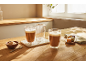 Dvě sklenice s kávou latte a sladkosti na dřevěném stole.