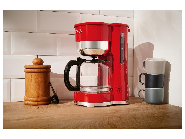 Červená kávovar KitchenAid na dřevěném stole.