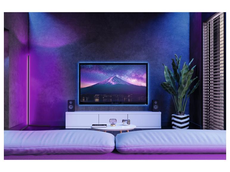 Televize s obrázkem hory Fuji, dva reproduktory a pohovka v obývacím pokoji s LED osvětlením.