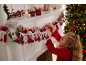 Dívka aranžuje adventní kalendář na krbové římse, s vánočními dekoracemi.