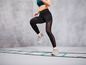 Žena ve sportovním oblečení běží po agility žebříku.