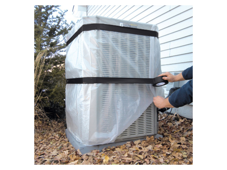 Osoba zakrývá klimatizační jednotku plastovou fólií a páskou.