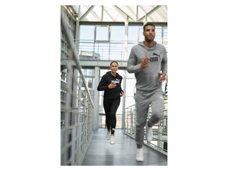 Dva lidé běhající uvnitř, oblečení v černých a šedých sportovních mikinách a teplácích.