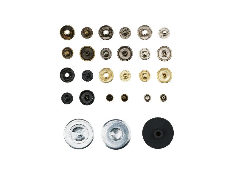 Sortiment různých kovových druků a knoflíků v různých velikostech a barvách.