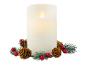 Bílá LED svíčka s efektem plamene obklopená větvičkami smrku, šiškami a červenými bobulemi.
