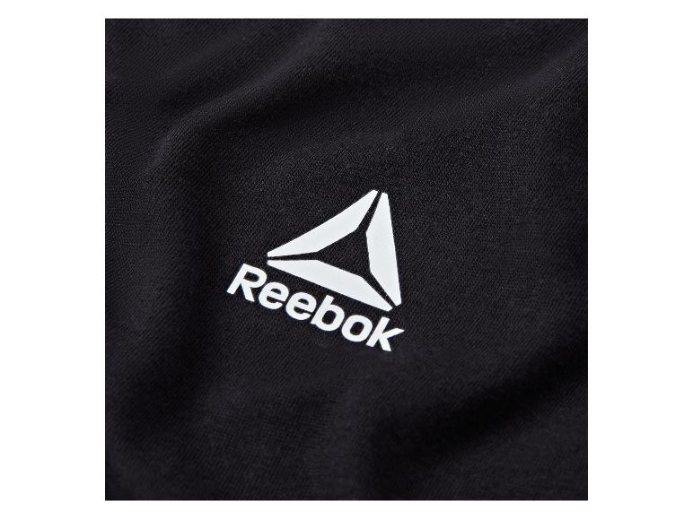 Detail černého textilu s bílým logem Reebok.