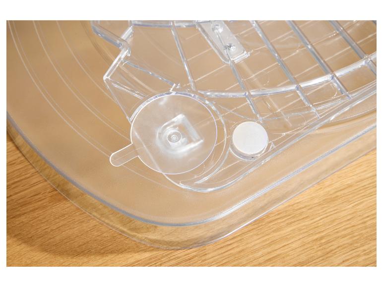 Průhledný plastový tác s mřížkovým vzorem a kulatými úchyty na dřevěném povrchu.
