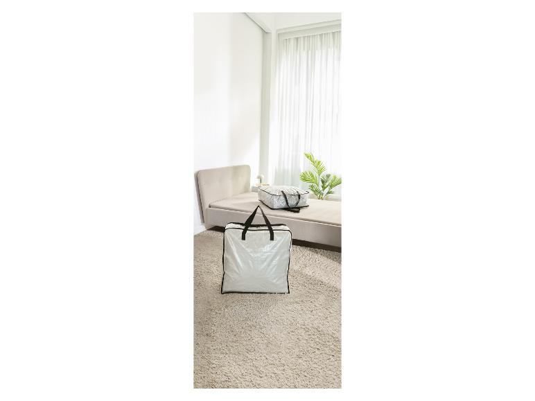 Bílé úložné tašky s černými uchy na béžovém koberci ve světlé ložnici.