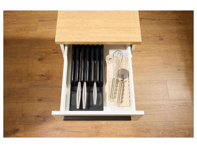Otevřená kuchyňská zásuvka s blokem na nože a kuchyňským náčiním, jako je metla a kráječ na pizzu.