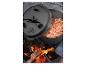 Litina Dutch Oven s chilli vařící se na otevřeném ohni, víko částečně otevřené.