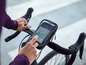 Ruka používá smartphone v držáku telefonu Crivit na řídítkách kola.