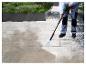 Osoba používá vysokotlaký čistič Parkside k čištění terasy.