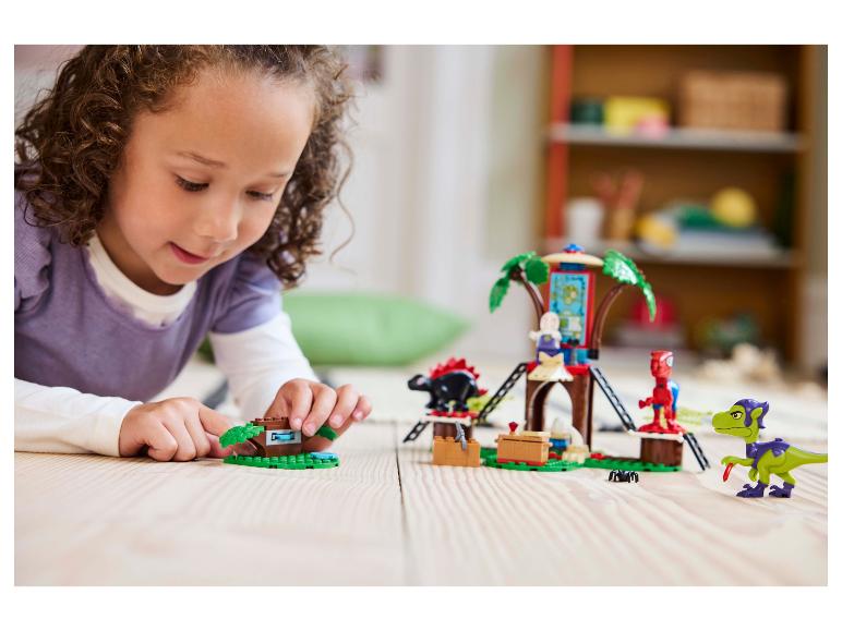 Mladá dívka si hraje se sadou LEGO DUPLO domeček na stromě a figurkami dinosaurů.