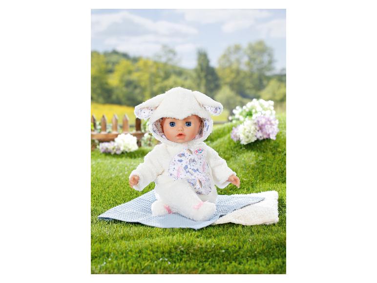 Panenka BABY born v bílém kostýmu jehněte sedí na modré dece na trávě.