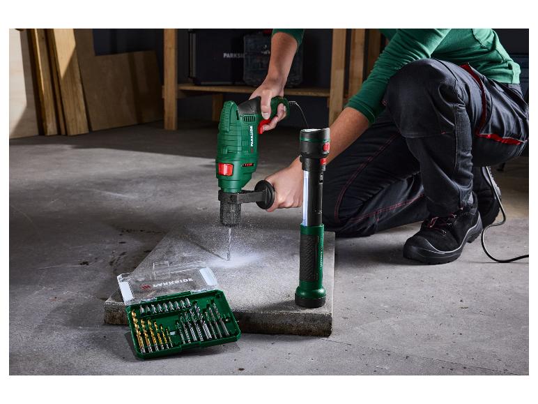 Osoba používá vrtačku Parkside k vrtání do betonové desky, sady vrtáků jsou poblíž.