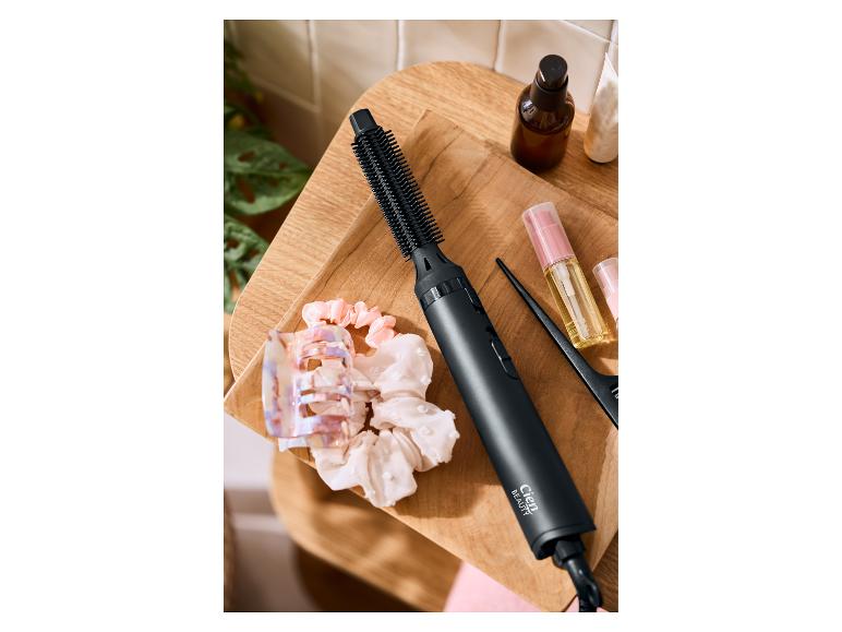 Horkovzdušný kartáč Cien Beauty, vlasové doplňky a produkty péče o vlasy na dřevěném podnosu.