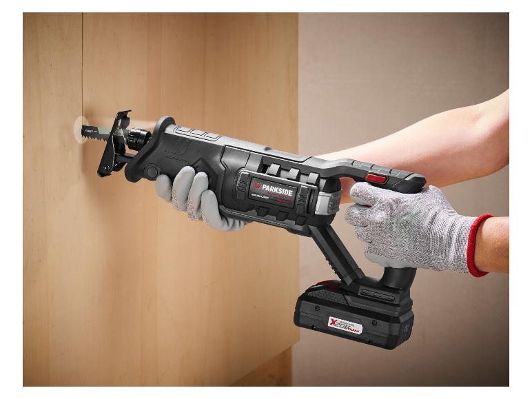 Osoba používá akumulátorovou pilu k vyříznutí otvoru do dřevěné stěny.