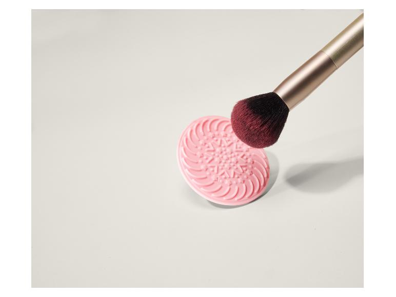 Růžová podložka na čištění make-up štětců s make-up štětcem.